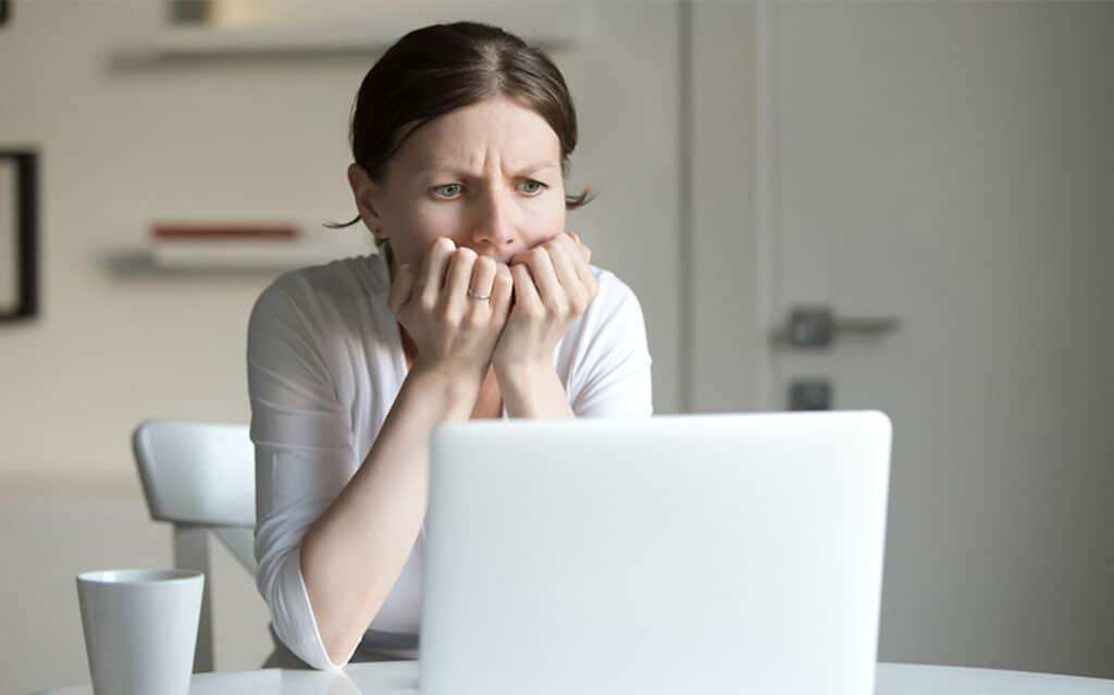 Image of woman in front of computer looking anxious about CTV ad fraud